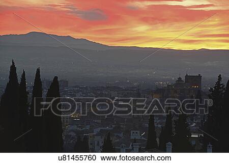 Stock Image - "Cityscape and hill at sunset, red yellow sky". Fotosearch