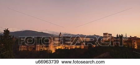 Stock Photo - "Cityscape with illuminated castle at dusk, pink sky". Fotosearch