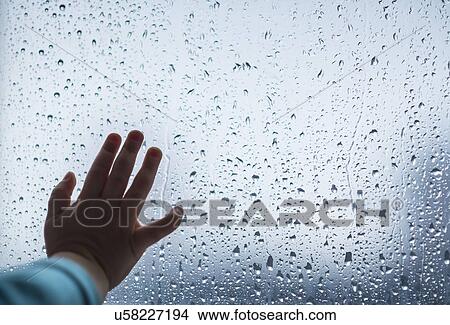 Picture - Close-up of girl's hand on wet window. Fotosearch