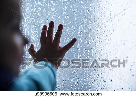 Stock Photograph - Close-up of girl's hand on wet window. Fotosearch