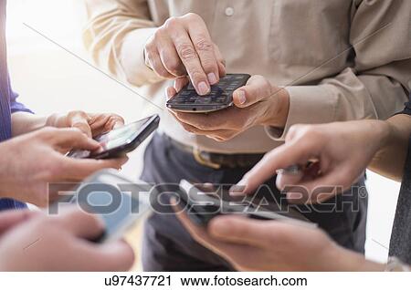 Close up of hands of men and women using smartphones together View Large Photo Image Stock Image - Close up of hands of men and women using smartphones together. Fotosearch