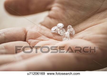 Stock Photo - Close up of man's hand holding diamonds. Fotosearch