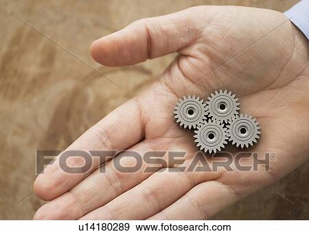 Close up of man's hand holding metal cogs View Large Photo Image Stock Photo - Close up of man's hand holding metal cogs. Fotosearch