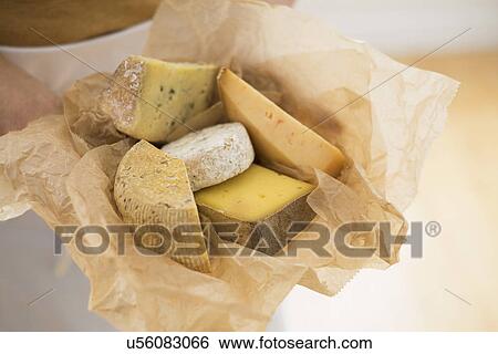 Stock Photograph - Close up of man's hand holding slices of cheese in paper. Fotosearch