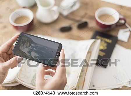 Close up of man's hand holding smartphone above map View Large Photo Image Stock Image - Close up of man's hand holding smartphone above map. Fotosearch