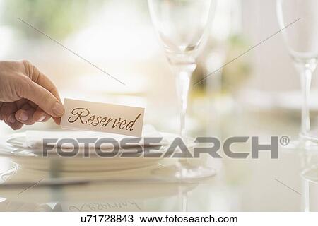 Stock Image - Close up of man's hand setting place in restaurant. Fotosearch