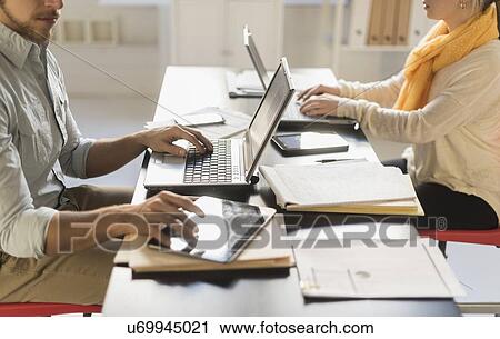 Close up of young man and woman working with laptops at desk View Large Photo Image Stock Image - Close up of young man and woman working with laptops at desk. Fotosearch