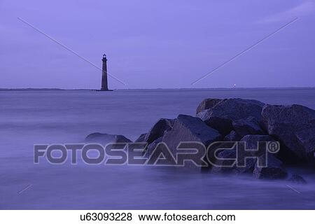 Stock Photo - Coastal rocks and lighthouse silhouetted as dusk. Fotosearch