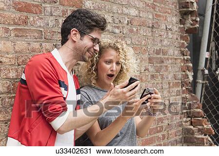 Stock Image - Couple sharing messages on cell phones. Fotosearch
