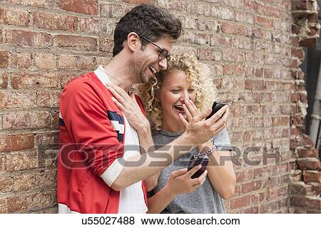 Couple sharing messages on cell phones View Large Photo Image Stock Photo - Couple sharing messages on cell phones. Fotosearch