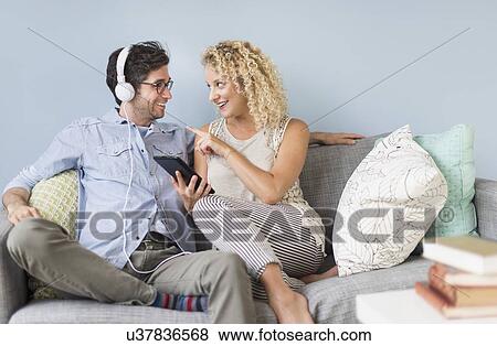 Couple sitting on sofa listening to music View Large Photo Image Stock Photo - Couple sitting on sofa listening to music. Fotosearch