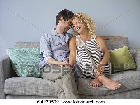 Stock Photo - Couple sitting on sofa. Fotosearch