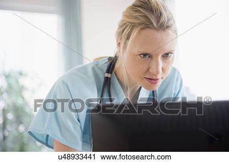 Stock Image - Doctor looking at computer monitor. Fotosearch