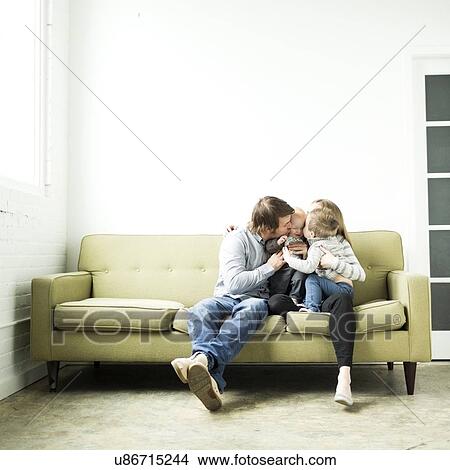 Picture - Family embracing on sofa. Fotosearch