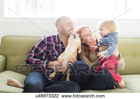 Stock Image - Family with son (2-3) and pug on sofa. Fotosearch