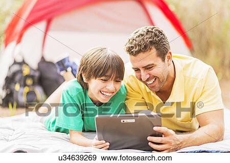 Stock Photo - Father and son (12-13) camping. Fotosearch