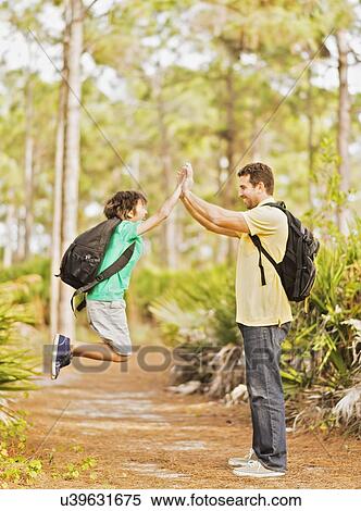 Father and son (12-13) doing high five in forest View Large Photo Image Stock Photography - Father and son (12-13) doing high five in forest. Fotosearch