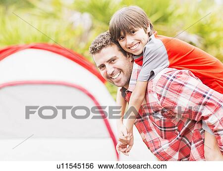 Stock Photograph - Father and son (12-13) piggy back . Fotosearch