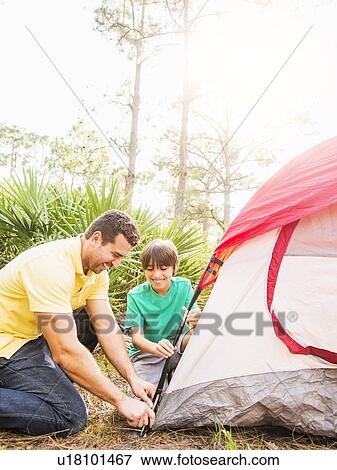 Stock Photo - Father and son (12-13) setting up tent. Fotosearch
