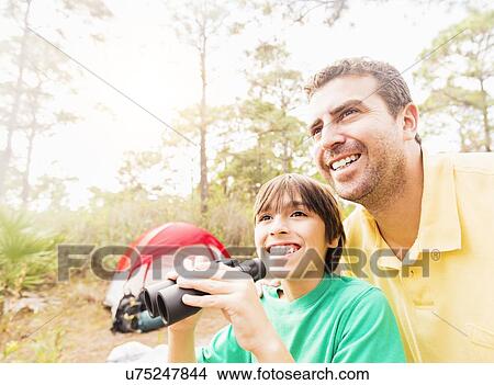 Father and son (12-13) using binoculars View Large Photo Image Picture - Father and son (12-13) using binoculars . Fotosearch