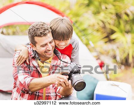Stock Image - Father and son (12-13) using digital camera. Fotosearch