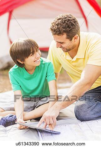 Father and son (12-13) using digital table at camping View Large Photo Image Stock Image - Father and son (12-13) using digital table at camping. Fotosearch