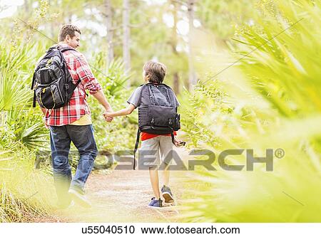 Stock Image - Father and son (12-13) walking in forest. Fotosearch