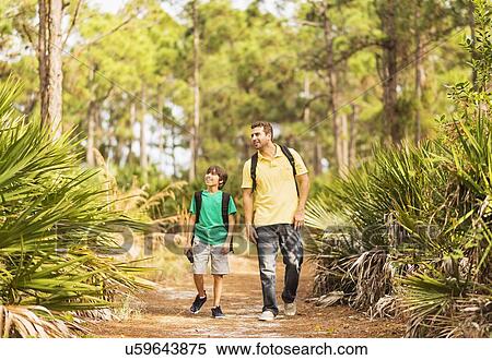 Stock Photography - Father and son (12-13) walking through forest. Fotosearch