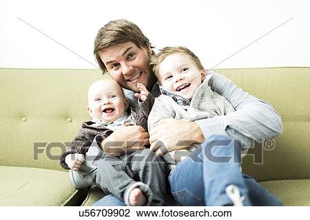 Stock Image - Father embracing two sons (6-11 months and 2-3 years). Fotosearch