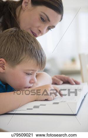 Stock Image - Female teacher and schoolboy (6-7) in classroom. Fotosearch