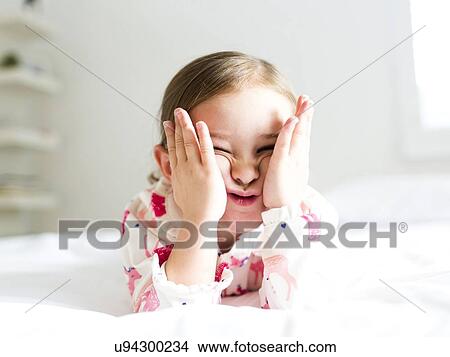 Girl (2-3) lying on bed pulling funny face View Large Photo Image Picture - Girl (2-3) lying on bed pulling funny face. Fotosearch