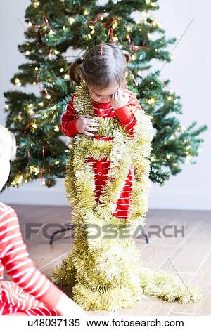 Stock Photography - Girl (4-5) decorating christmas tree. Fotosearch