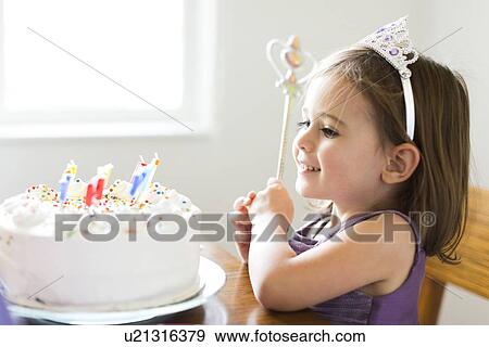 Stock Photo - Girl (4-5) looking at birthday cake. Fotosearch