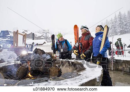 Stock Image - Group of friends with bonfire in winter. Fotosearch