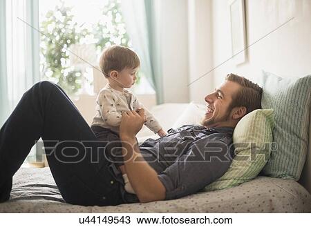 Happy father playing with little son (2-3 years) on bed View Large Photo Image Stock Image - Happy father playing with little son (2-3 years) on bed. Fotosearch