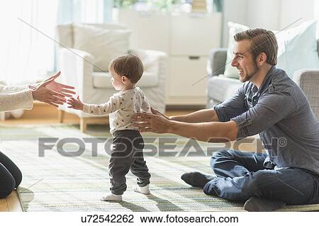 Happy parents helping little son (2-3 years) walking in living room View Large Photo Image Stock Image - Happy parents helping little son (2-3 years) walking in living room. Fotosearch