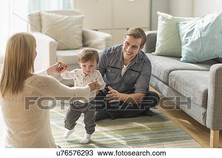 Happy parents helping little son (2-3 years) walking in living room View Large Photo Image Stock Image - Happy parents helping little son (2-3 years) walking in living room. Fotosearch