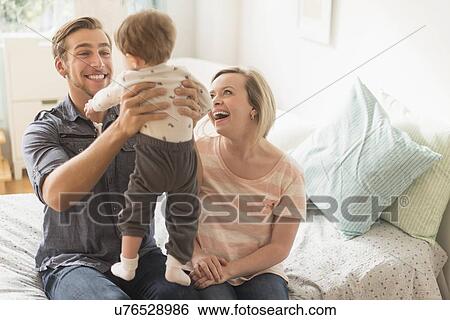 Happy parents playing with little son (2-3 years) on bed View Large Photo Image Stock Photograph - Happy parents playing with little son (2-3 years) on bed. Fotosearch