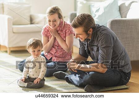 Picture - Happy parents sitting with little son (2-3 years) on floor. Fotosearch