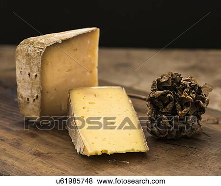 Stock Photo - "Hard cheese slices and truffle on wooden table, studio shot". Fotosearch
