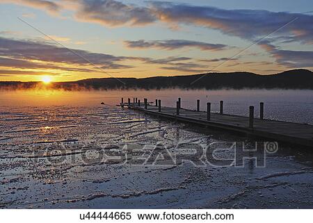 Stock Photography - "Jetty on frozen lake, hills in background at sunrise". Fotosearch