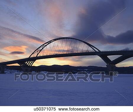 Stock Photography - "Lake Champlain Bridge linking New York and Vermont over a frozen Lake Champlain at Crown Point, snowed landscape at dusk". Fotosearch