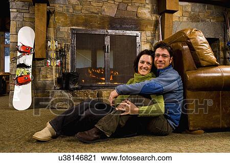 Stock Image - Man and woman hanging out in front of fireplace. Fotosearch