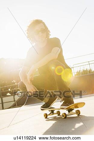 Picture - Man crouching on skateboard. Fotosearch