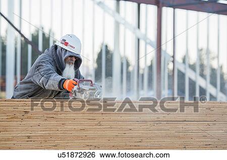 Stock Photograph - Man cutting wooden planks. Fotosearch