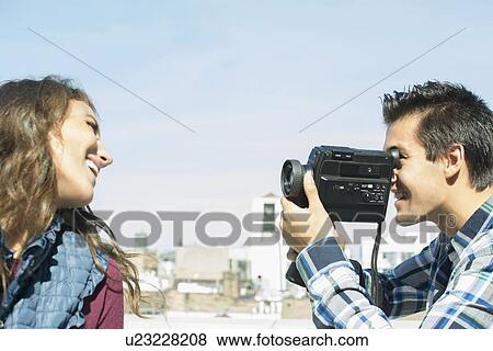 Stock Photo - Man filming his girlfriend on roof. Fotosearch
