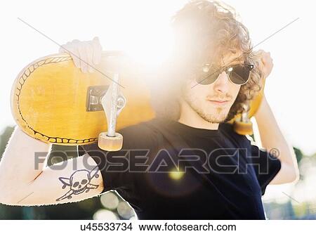 Man holding skateboard on his arms View Large Photo Image Picture - Man holding skateboard on his arms. Fotosearch