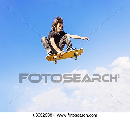 Man jumping on skateboard against sky and clouds View Large Photo Image Stock Photo - Man jumping on skateboard against sky and clouds. Fotosearch