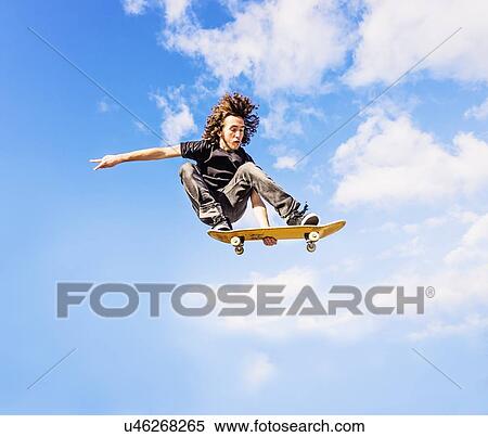 Man jumping on skateboard against sky and clouds View Large Photo Image Stock Photography - Man jumping on skateboard against sky and clouds. Fotosearch
