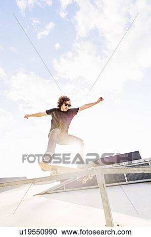 Stock Image - Man jumping on skateboard in skatepark. Fotosearch